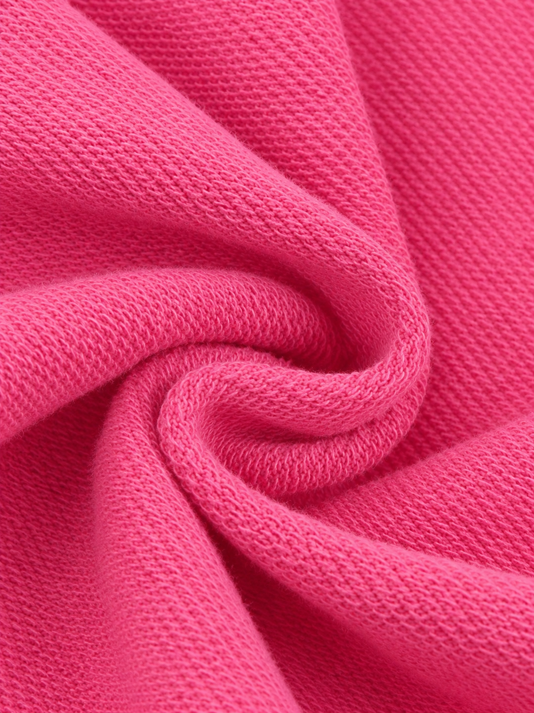 A close-up of bright pink textured fabric arranged in a spiral drape, showing the woven material detail.