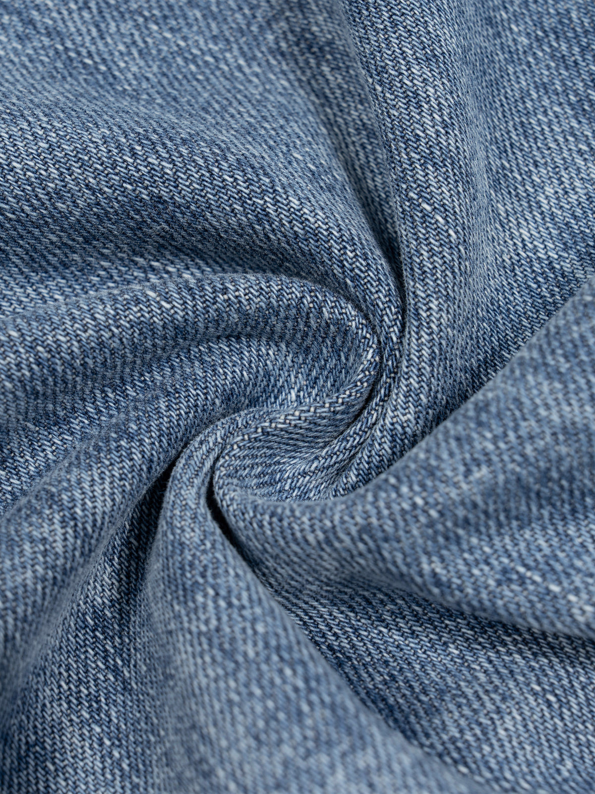 A close-up of textured blue denim fabric with a twisted swirl pattern, showing the woven twill weave and subtle lighter blue highlights.