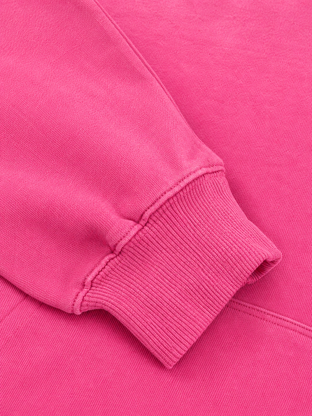 Close-up of a bright pink sweatshirt showing the ribbed cuff of a sleeve and the soft knit fabric texture.