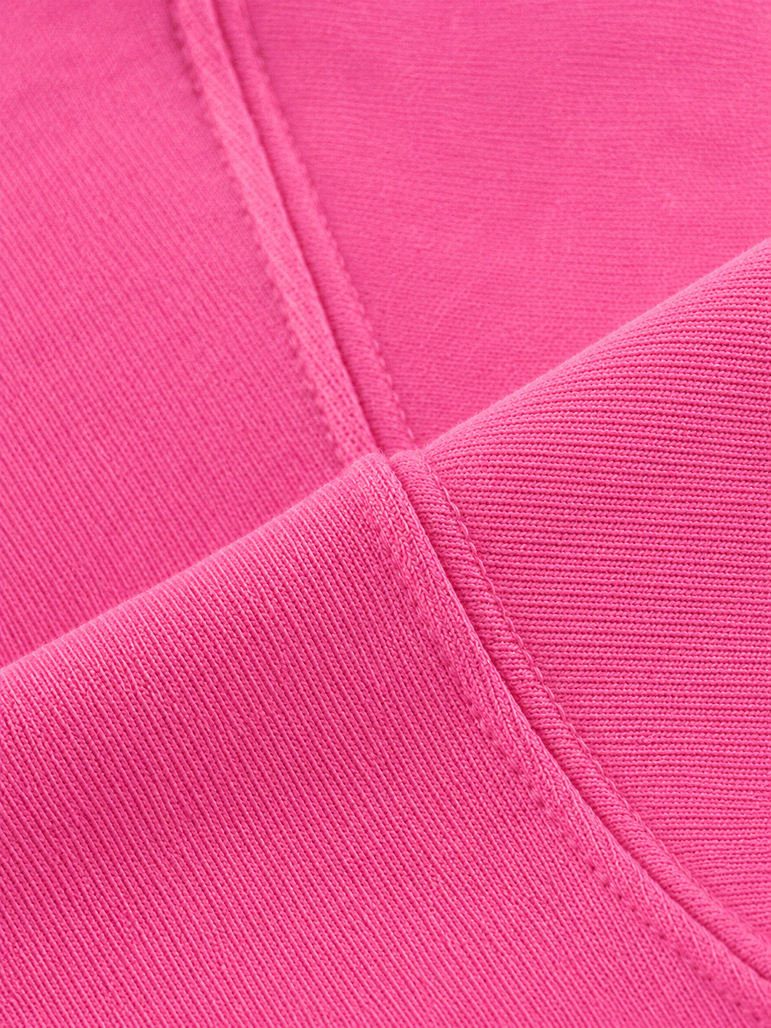 A close-up of bright pink ribbed fabric with visible stitching and a folded seam.