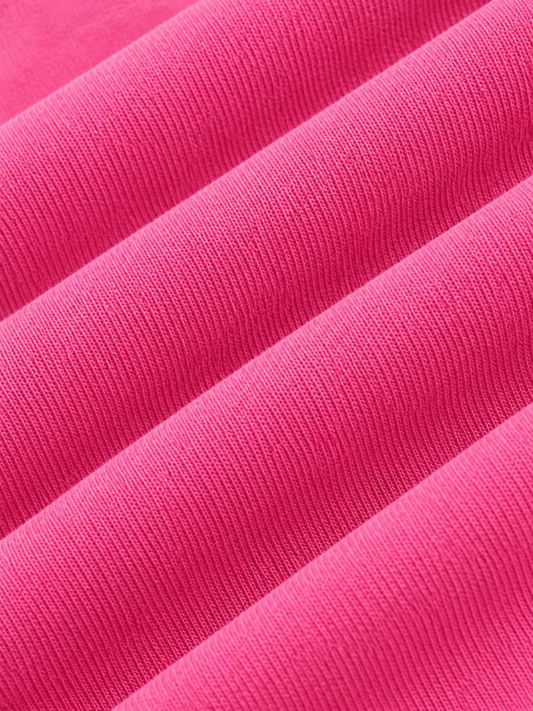 A close-up of bright pink ribbed knit fabric with soft diagonal folds and visible texture.
