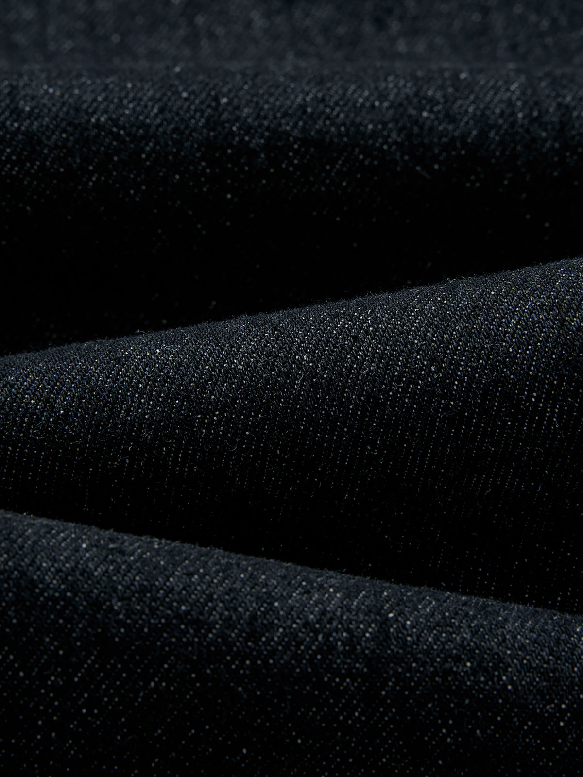 A close-up of dark charcoal gray textured fabric with soft folds.