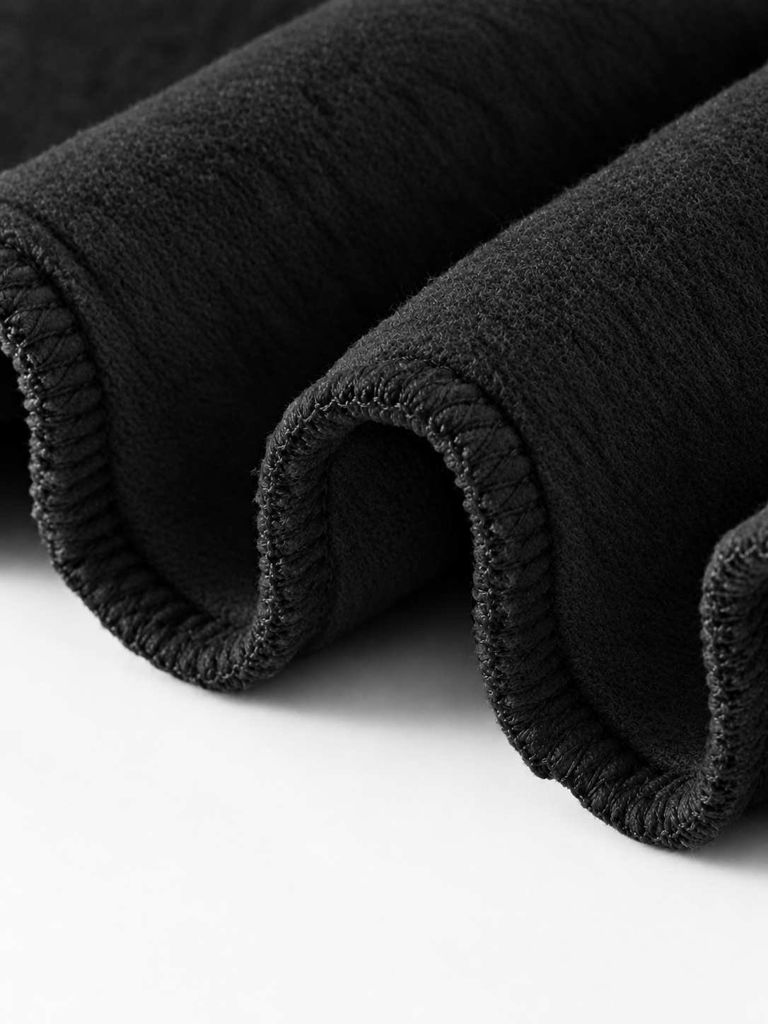 Close-up of a dark ribbed fabric, showing the soft texture and folded edges against a white background.