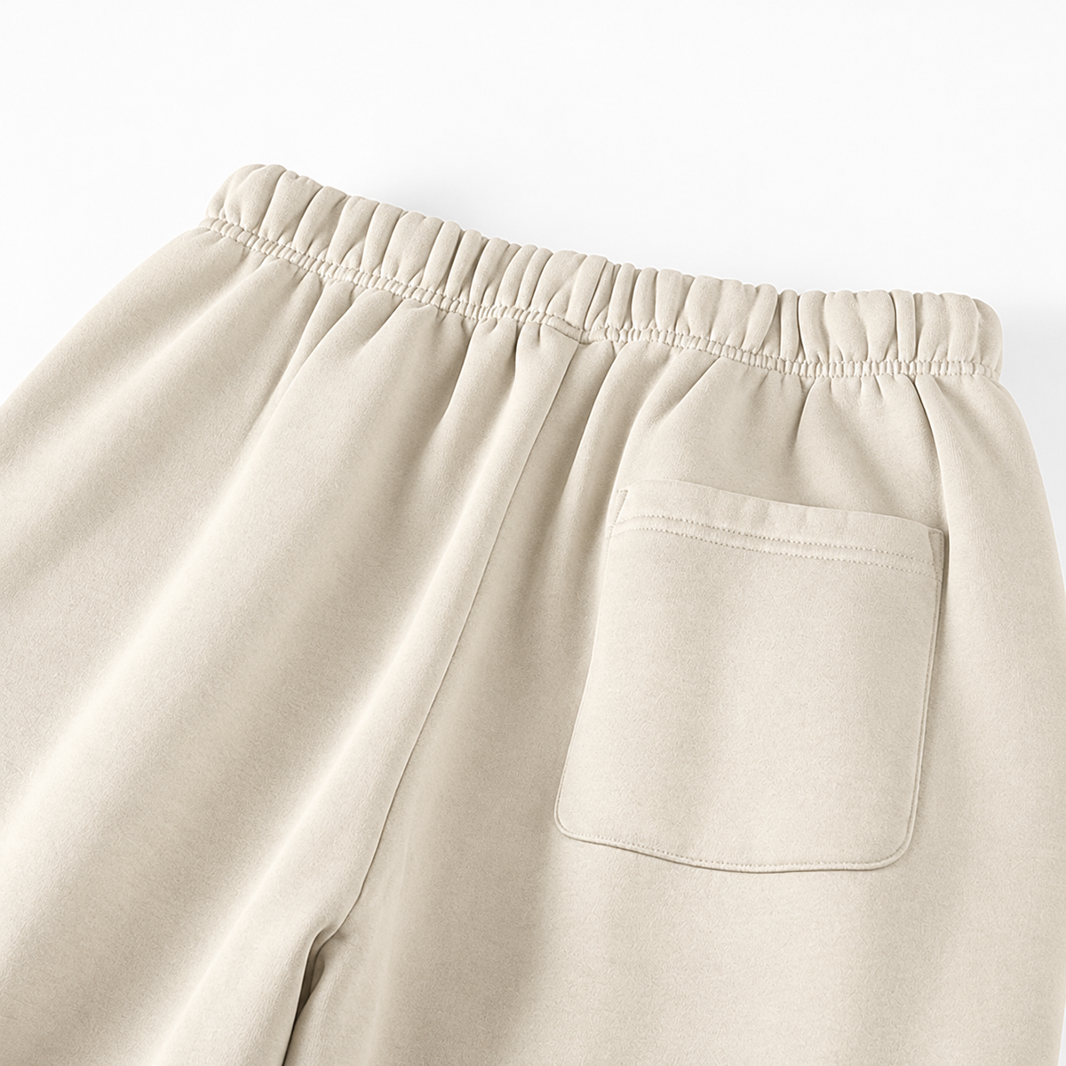 Close-up of a pair of light beige sweatpants showing the elastic waistband and a side pocket.