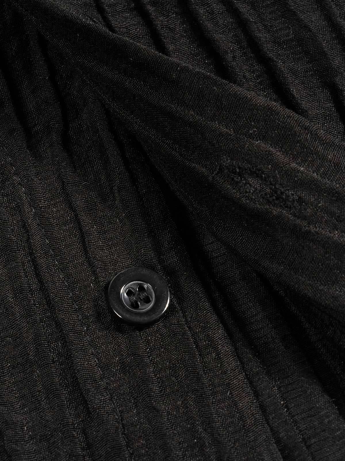 Close-up of a black button on textured fabric