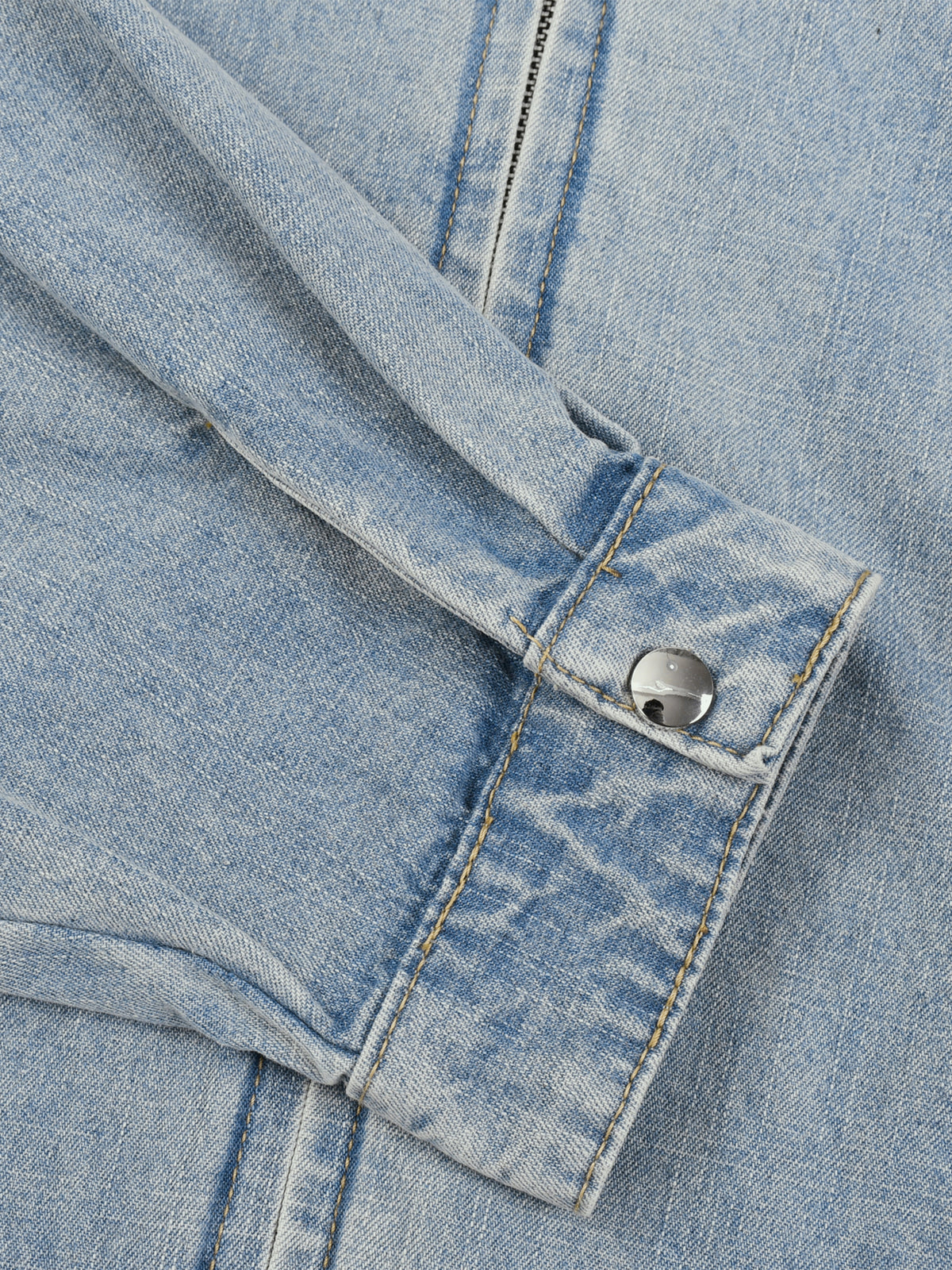 Close-up of a blue denim jacket with a button on a matching fabric background