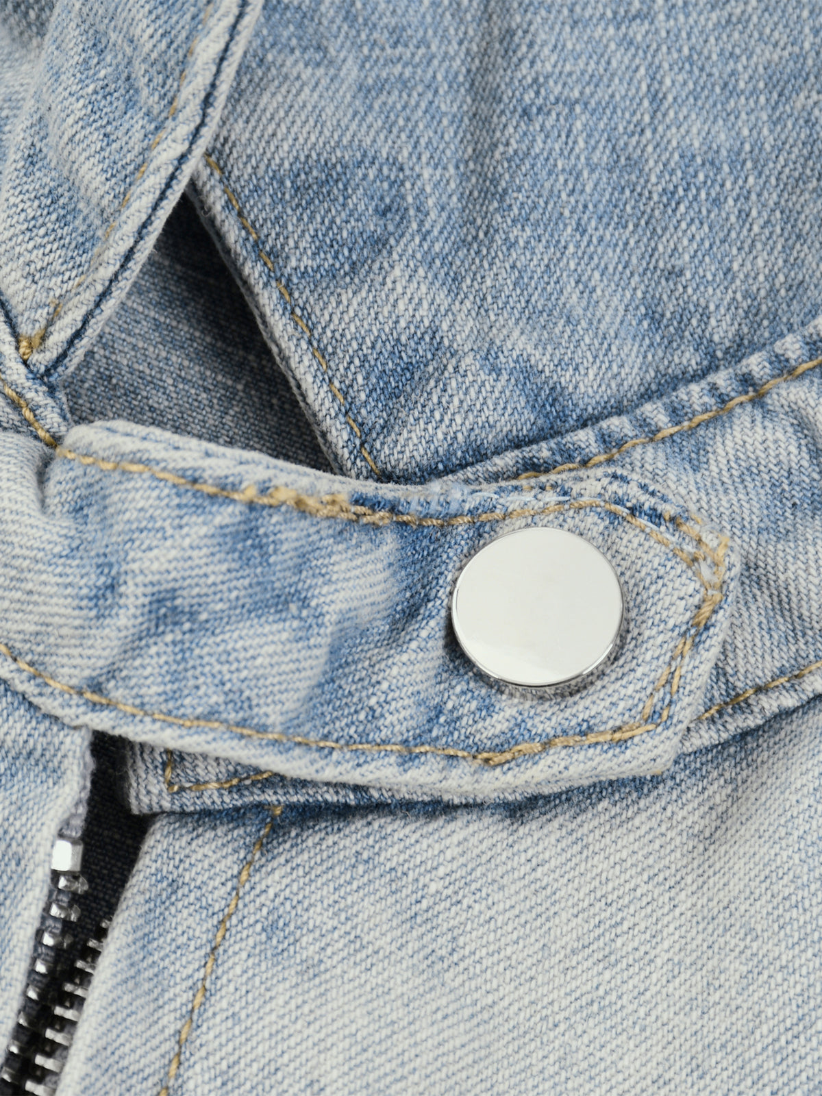 Close-up of a blue denim jacket with a button and zipper.