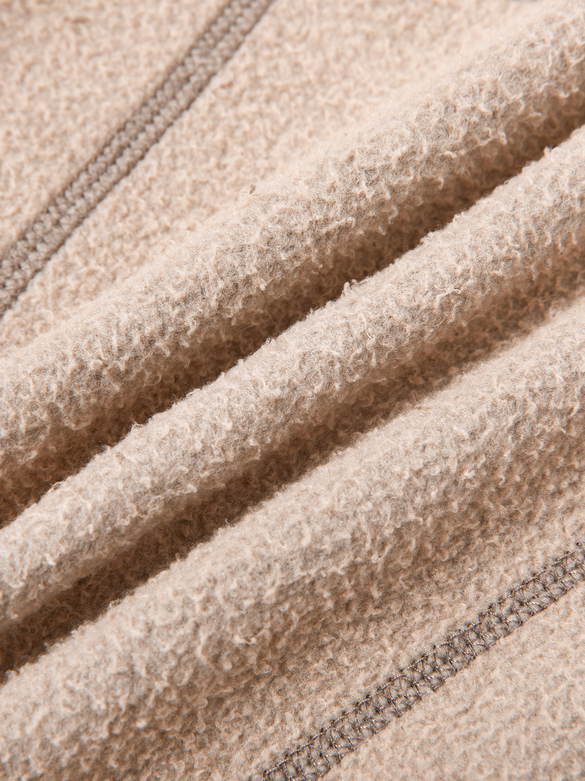 Close-up of beige fleece fabric with stitching details
