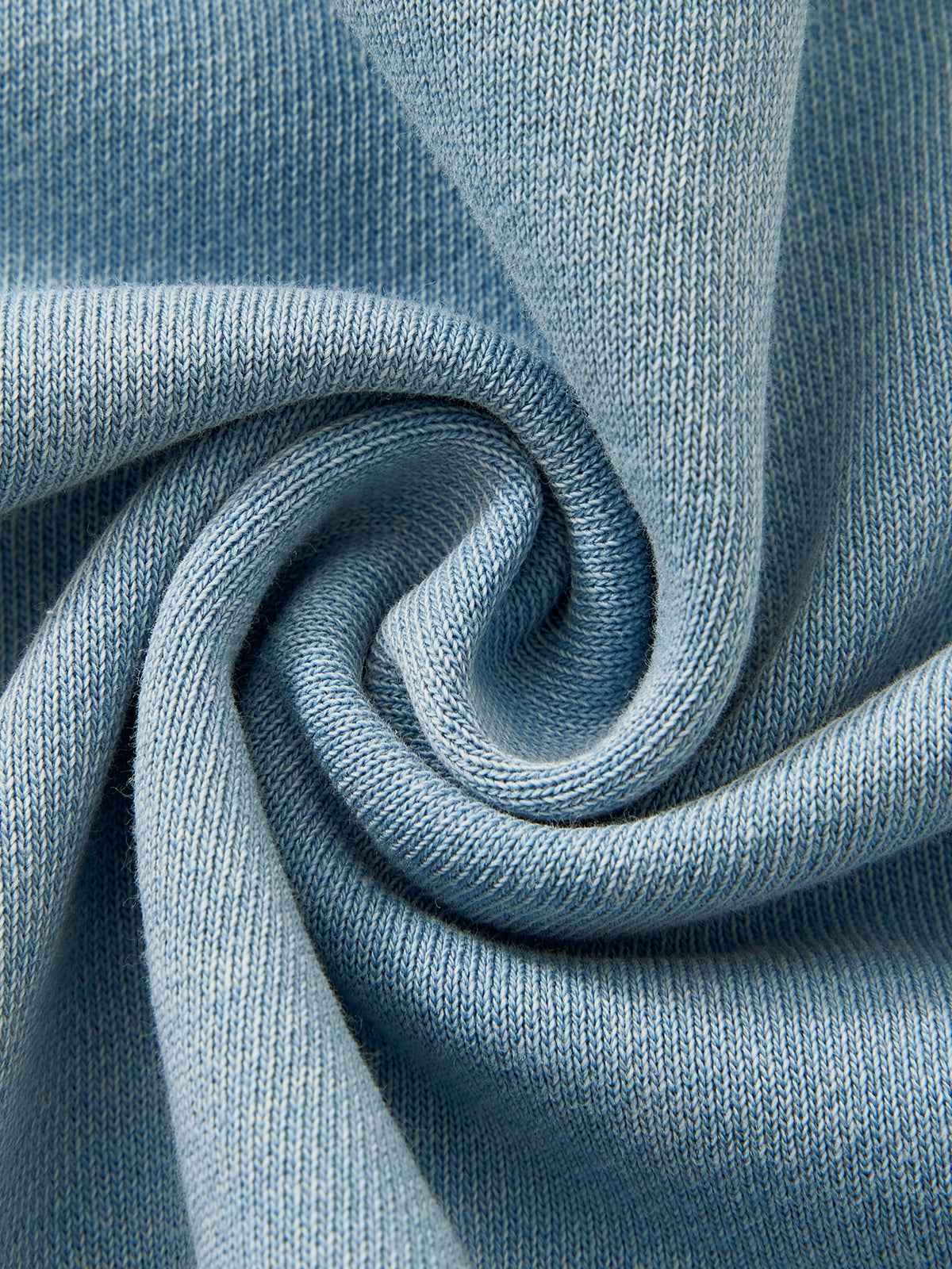 A close-up of light blue knit fabric arranged in a spiral drape, showing the texture and color of the material.