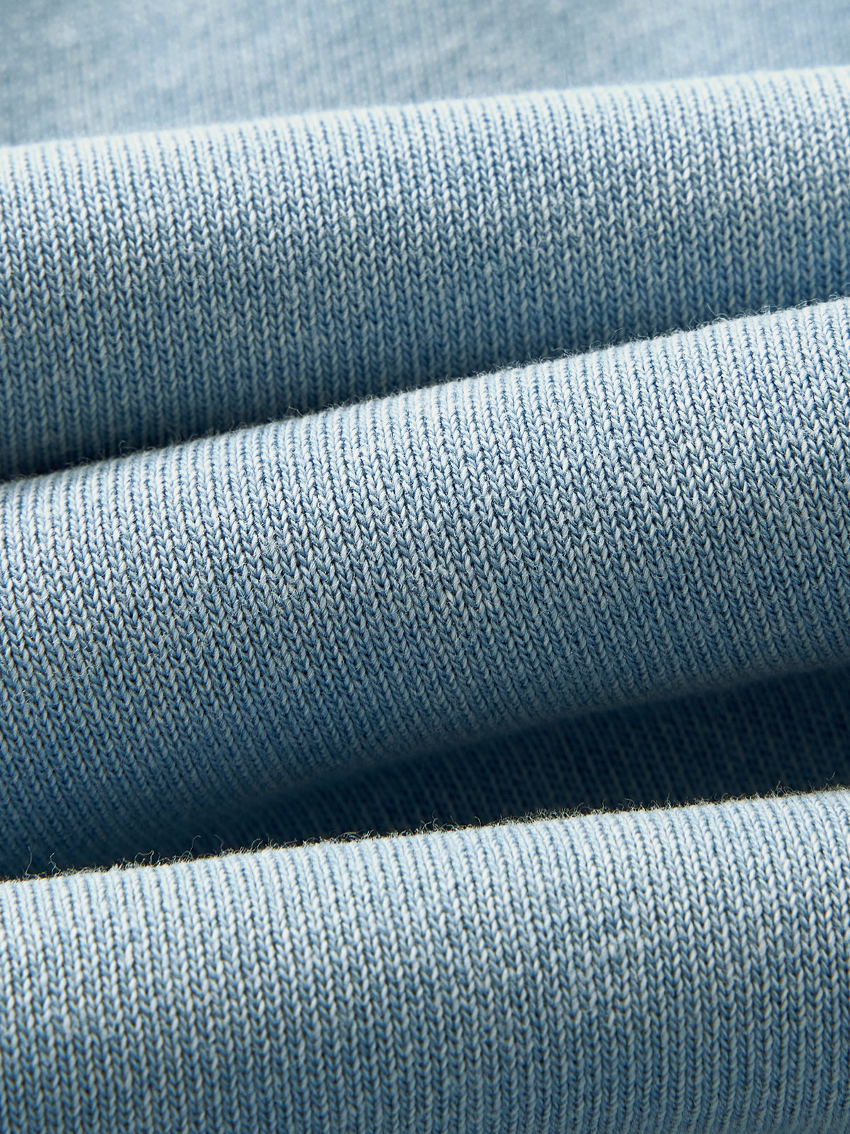 A close-up of light blue ribbed knit fabric, showing the texture and folds of the material.