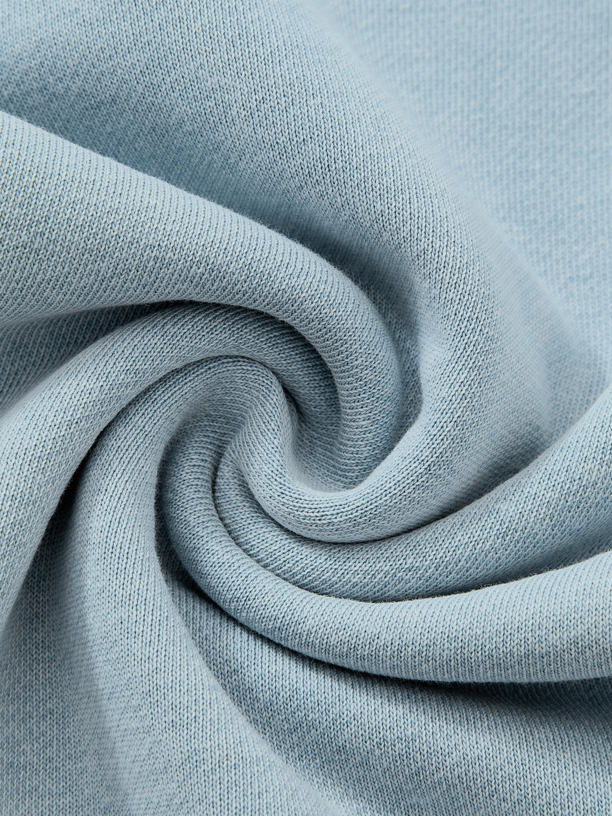 A close-up of light blue knit fabric arranged in a spiral drape, showing the texture and color of the material.