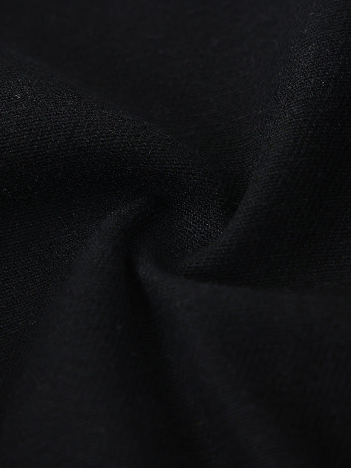 A close-up of black fabric with soft folds showing a fine woven texture.